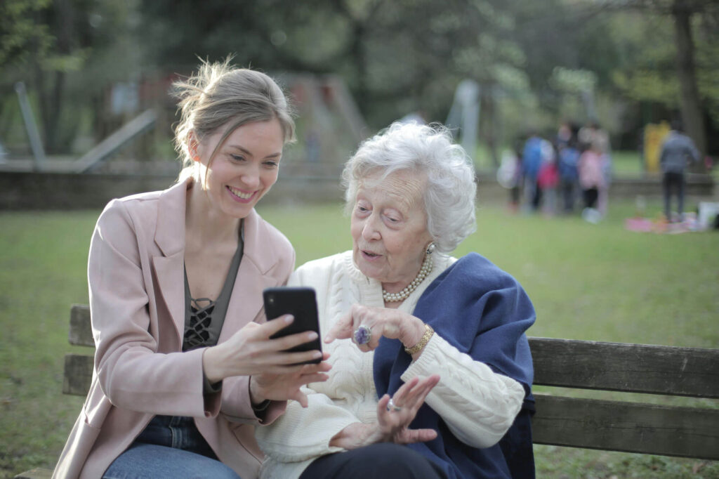 Young woman showing an old woman a phone