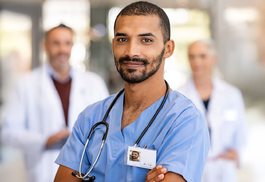 Smiling nurse with doctors in the background.